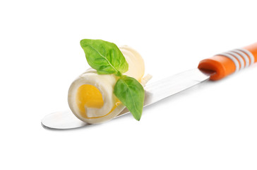 Delicious butter curl with basil leaves on shovel isolated on white, closeup