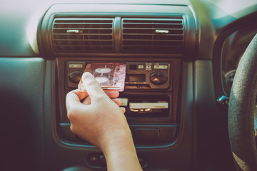 Woman hand holding tape cassette in car for driving listen music - vintage color tone effect.