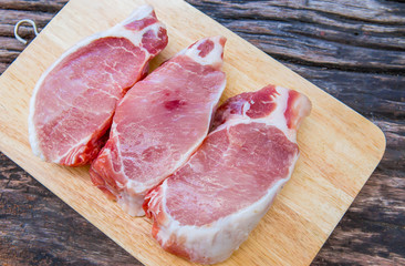 Raw pork shoulder chop on wooden board