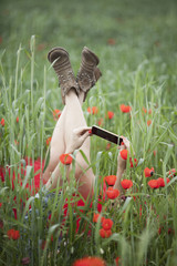 Girl in poppy field with the phone. feet up