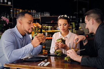 Three people eats sandwiches.