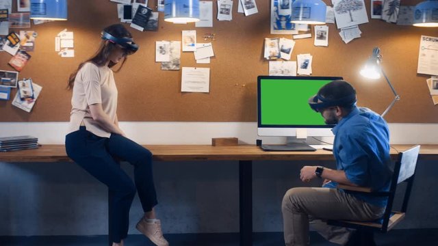 Young adult Caucasian colleagues using holographic augmented reality glasses together, creating a model on a computer screen. Green screen chroma key. 4K UHD RAW edited footage