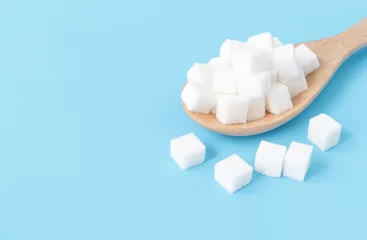 Foto op Plexiglas Closeup sugar cubes on wooden spoon white blue background © mraoraor