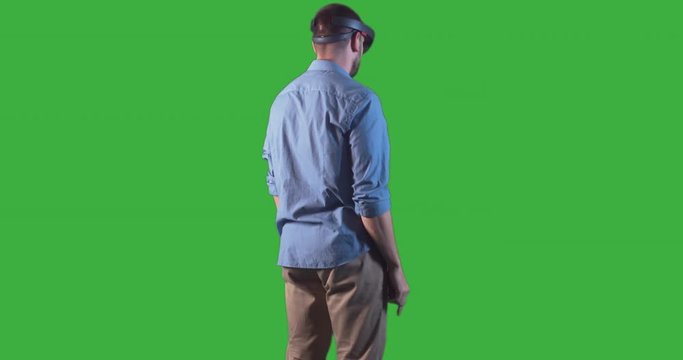 Young adult Caucasian male using holographic augmented reality glasses. Green screen chroma key. Left side key light. 4K UHD RAW edited footage