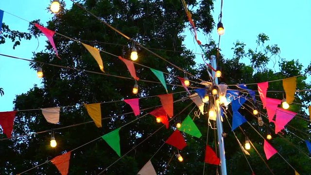 Festival event decoration. Colorful flags and light hanging over pole in evening sky