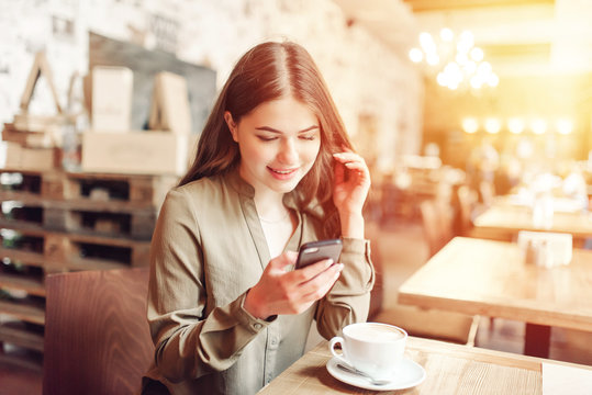 Pretty Girl Using Cell Phone Smiles.In caffe.With coffe and pizza.