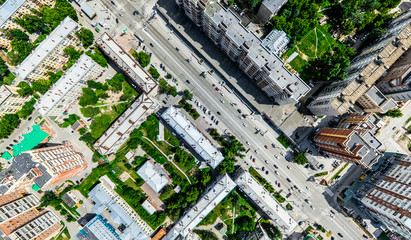 Fototapeta premium Aerial city view with crossroads and roads, houses, buildings, parks and parking lots, bridges. Helicopter drone shot. Wide Panoramic image.
