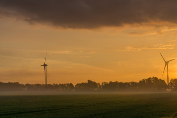 wind wheels at sunrise and fog with dark clouds