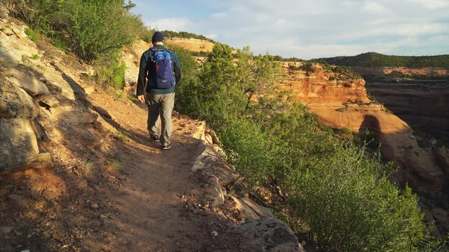 Male hiker walking on Ute Canyon trail in Colorado National Monument, early morning springtime scenery
