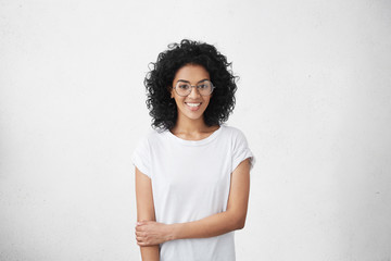 Relaxed carefree smiling young woman wearing white t-shirt and glasses having positive cheerful...