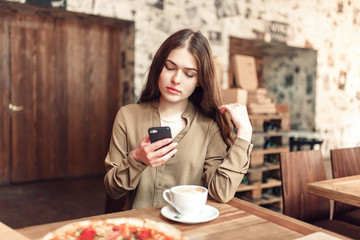 Pretty girl using cell phone.In caffe.With coffe.