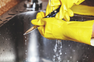 Hands in yellow rubber gloves, wash small knife