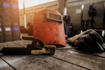 Vintage tone of equipment on wooden desk with man working in workshop background. Retro filter effect  low light.