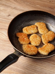 Chicken nuggets with sesame seeds on a frying pan