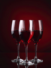 Three wineglasses with some wine on red