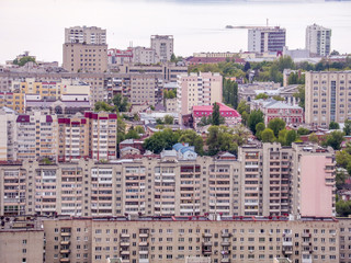 Fototapeta premium View of the city of Saratov from the mountain. The urban landscape, infrastructure, tenement houses, public buildings and streets, the Volga river on the horizon. Russian province.