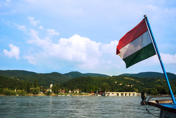 A view to a church at Visegrad, a small town at Hungary near Budapest from a ship at Danube, and a hungarian flag at the foreground.