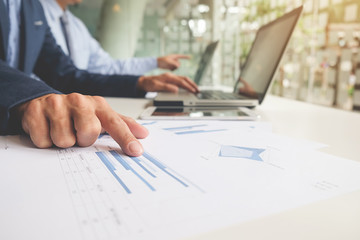 Business concept. Business people discussing the charts and graphs showing the results of their successful teamwork. Selective focus.