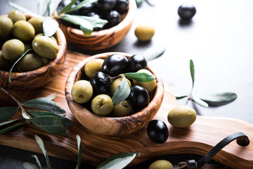 Black and green olives in wooden bowl