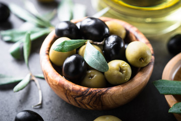 Black and green olives in wooden bowl