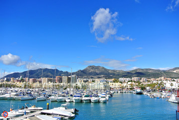 Fototapeta na wymiar BENALMADENA, SPAIN - FEBRUARY 13, 2014: Benalmadena Marina port, a view to piers with yachts, Mediterranean sea and mountains at the background.