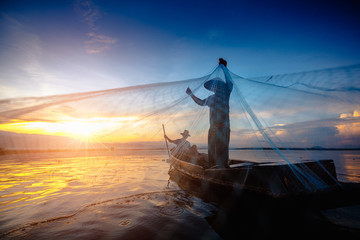 Silhouette of fishermen using nets to catch fish at the lake in the morning