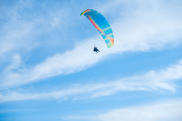 Paragliders in bright blue sky, tandem of instructor and beginner