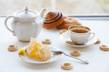Cups of tea with honey on a plate and teapot, white baackground