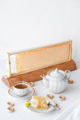 Honey with honeycomb and tea with teapot and flowers on the background, place for wording