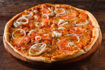 Appetizing fresh tasty pizza with ham, onion, tomato and cheese served on wooden table, closeup. National italian food, restaurant menu photo.