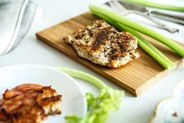 Grilled chicken breast with herbs and vegetables on a wooden cutting board, horizontal.