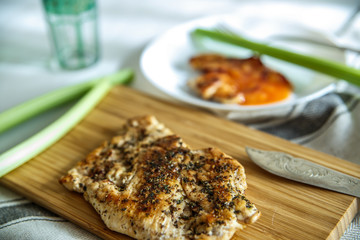 Grilled chicken breast with herbs and vegetables on a wooden cutting board, horizontal.