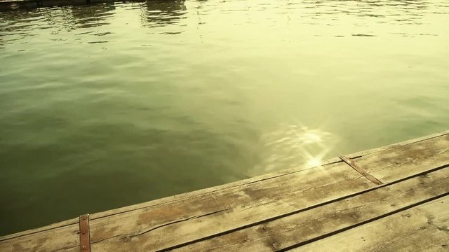 Ripples waves on lake & wood piers,sun light reflection in water.