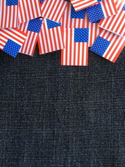Obraz premium Miniature paper flags of the United States of America on a blue denim material background with copy space