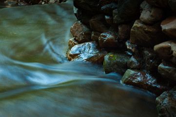 Waterfall and rocks with leaf in dark low key and long exposure with copy space