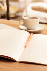 Coffee cup, notebook and pen on the wooden table