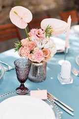 Flower table decorations for holidays and wedding dinner. Table set for holiday, event, party or wedding reception in outdoor restaurant.