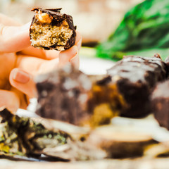 Homemade raw chocolate candy. A piece of Snickers bars in a hand.