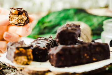 Homemade raw chocolate candy. A piece of Snickers bars in a hand.