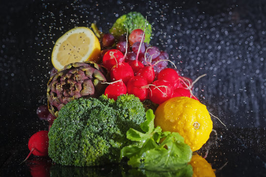 Verschiedenes Gem&uuml;se und Obst auf dunkem Hintergrund mit vielen Wassertropfen