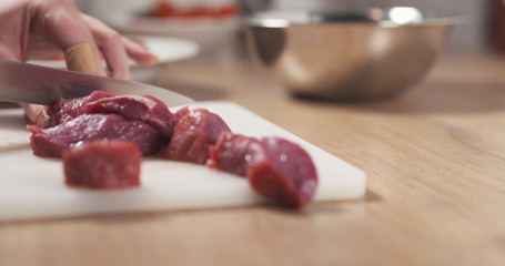 young female hand cutting raw beef with a knife on plastic board, 4k photo