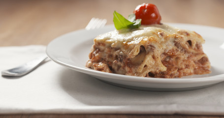 homemade lasagna portion on white plate on wood table, 4k photo