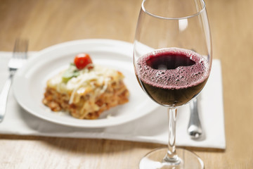 homemade lasagna with red wine on wood table, shallow focus