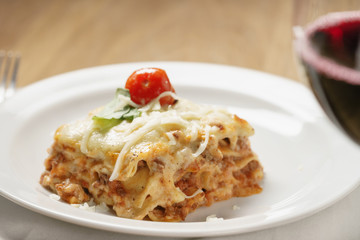 homemade lasagna with red wine on wood table, shallow focus