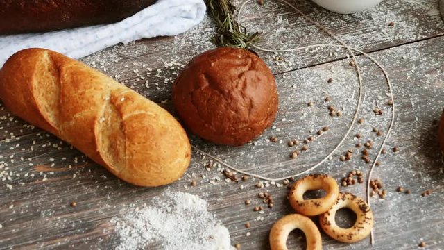 Different types of bread on wooden table dusted with flour. Slow pan. Concept of natural food.