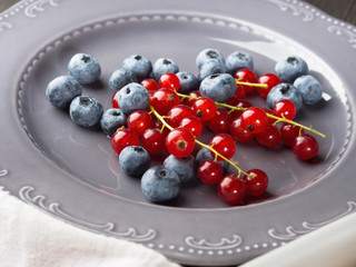 Naklejka na ściany i meble Fresh summer wild blueberries and red currants berries on rustic plate