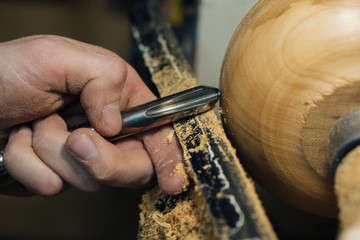 Wood carving, the master's hands work with a wooden surface, a professional does wood crafts