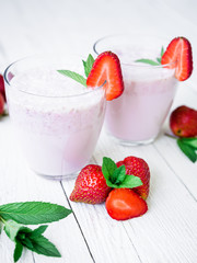 Fresh milkshake. Smoothie with strawberry on white rustic background.