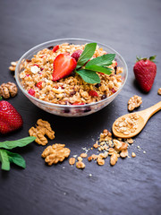 Oatmeal porridge with blueberries, strawberries, mint leaves and muesli on dark background. Top view. Diet breakfast.
