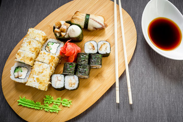 Fototapeta na wymiar Set sushi rolls, soy sauce and chopsticks on a grey background. Top view. Flat lay. Traditional food